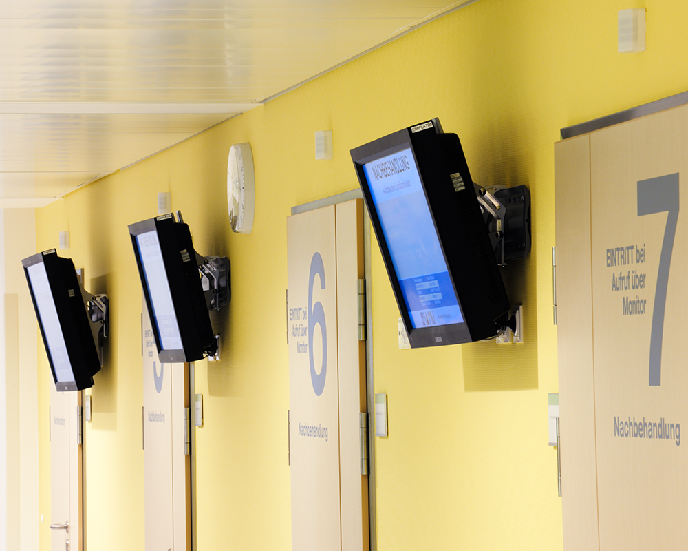 Man sieht Aufrufmonitore, die in der Unfallambulanz hängen. 