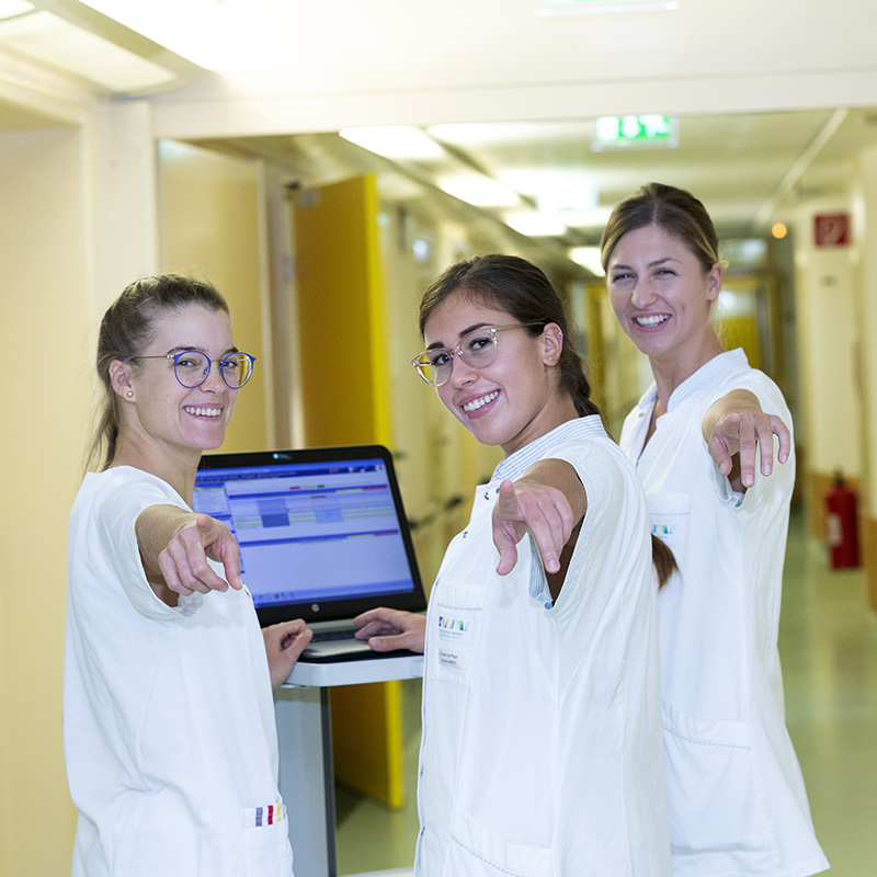 Drei Pflegekräfte mit einem Visitenwagen.