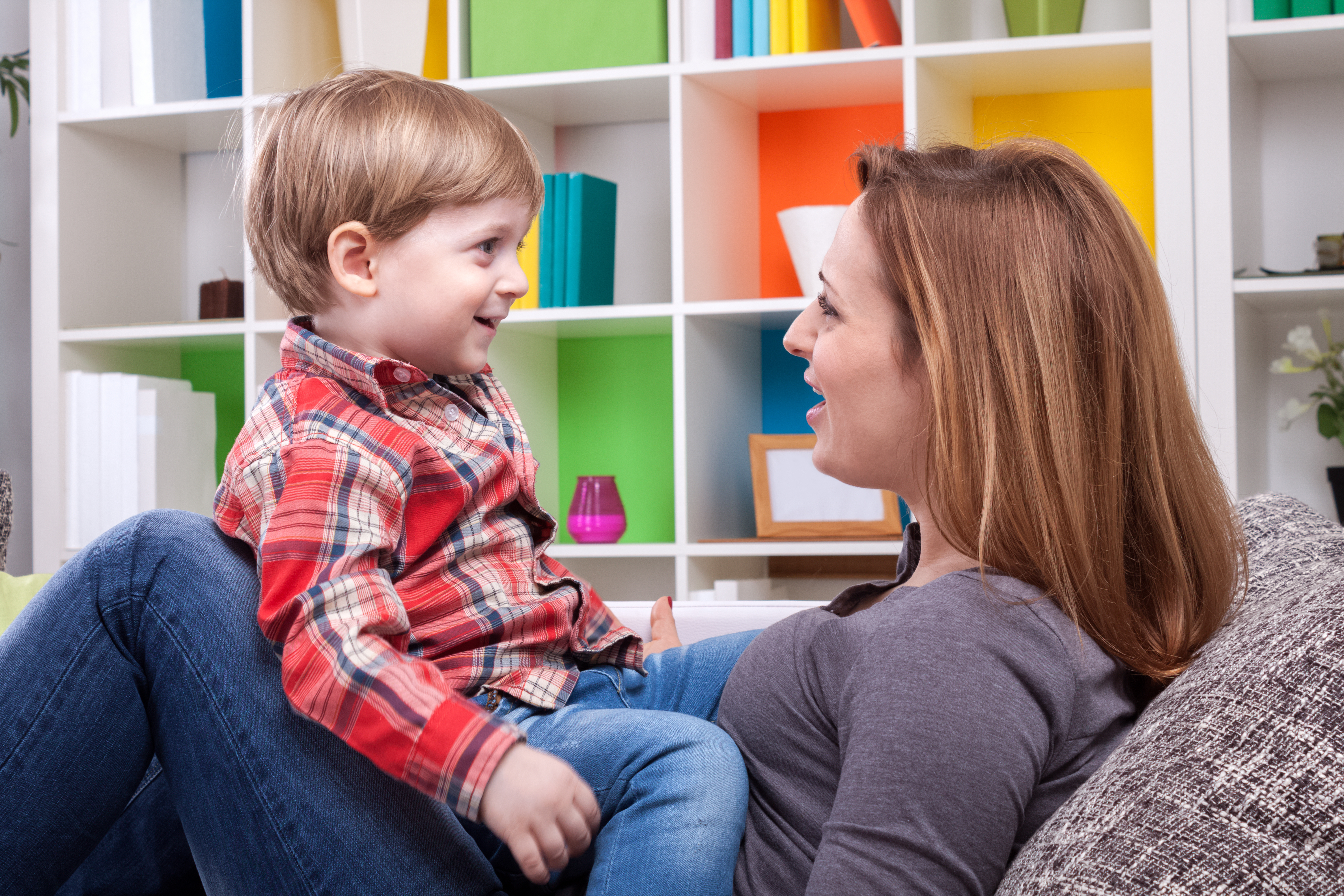 Das Foto zeigt eine sitzende Frau von der Seite, bei der ein in etwa 3 Jahre altes blondes Kind am Schoss sitzt.