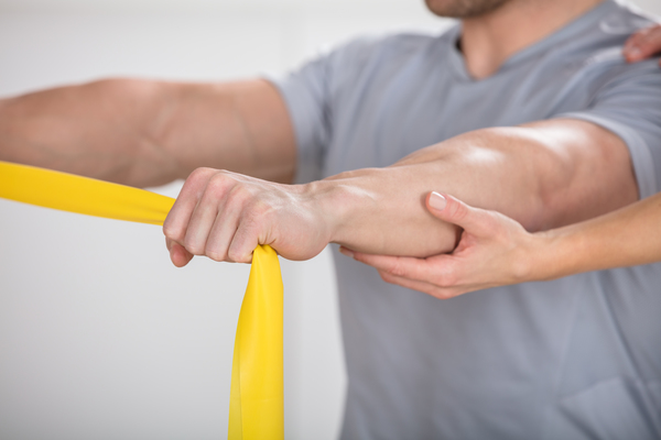 Close-up Of A Physiotherapist Giving Man A Training With Exercise Band