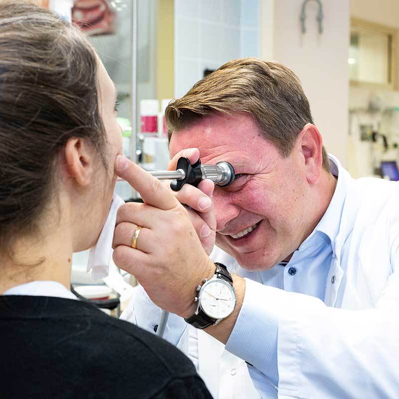 Arzt untersucht das Ohr einer Patientin mit einem Otoskop.