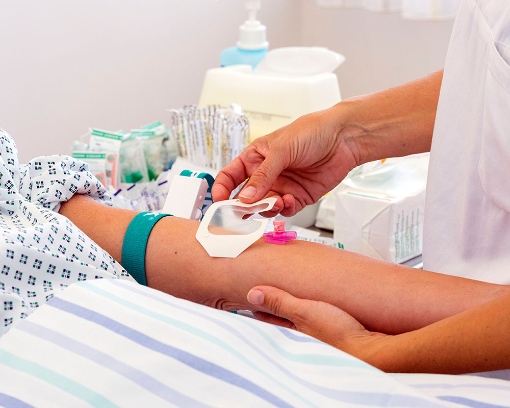 Man sieht einen Arm, der für eine Infusion vorbereitet wird. 