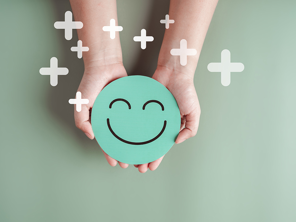 Das Bild zeigt Hände, die einen Smiley halten