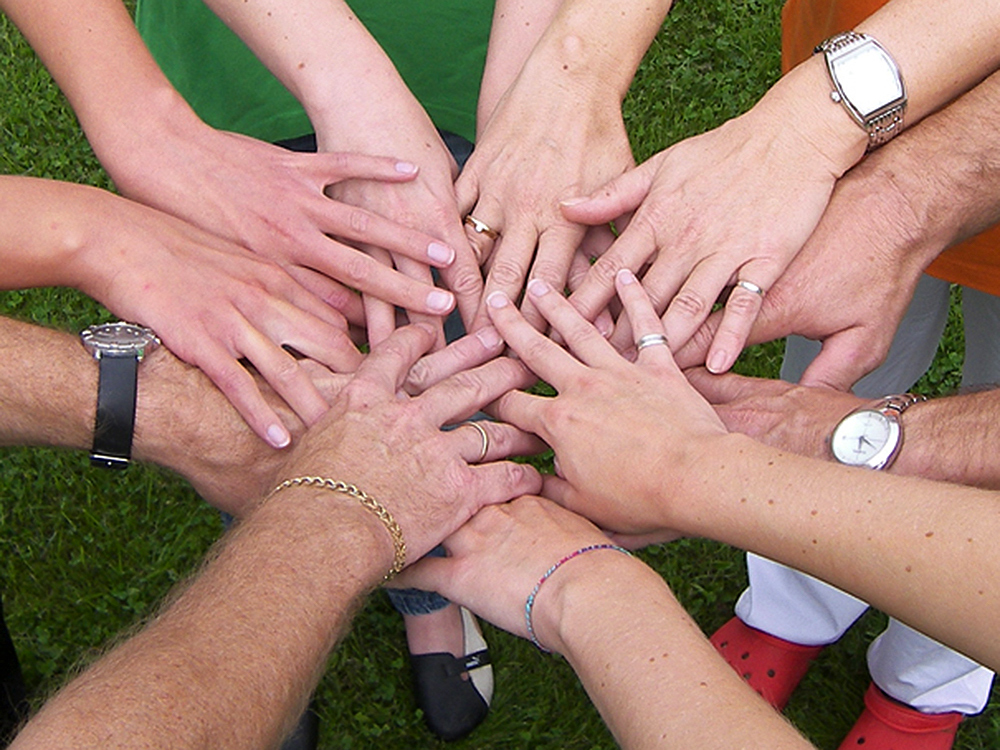 Das Bild zeigt Hände, die sich berühren und symbolisiert Zusammenhalt