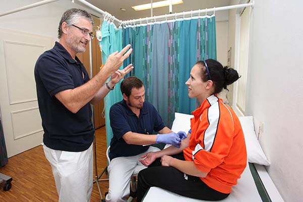 Arzt, Pfleger und gehoerlose Patientin bei einer Untersuchung.