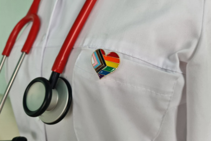 Silhouette of doctor in white coat with stethoscope and LGBT badge on pocket / Nadzeya - stock.adobe.com Silhouette of doctor in white coat with stethoscope and LGBT badge on pocket concept