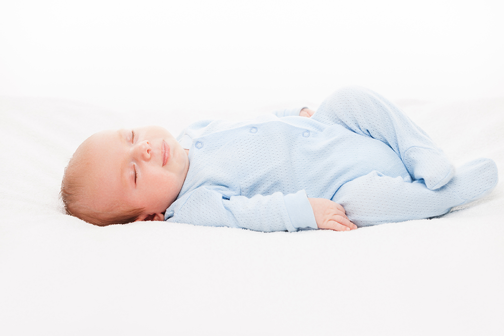 Little cute smiling newborn baby child sleeping bed white isolated