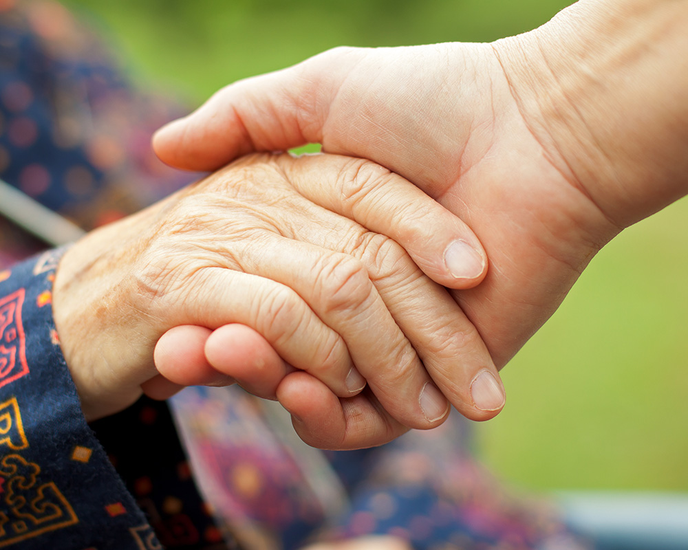 Doctor's hand holding a wrinkled elderly hand
