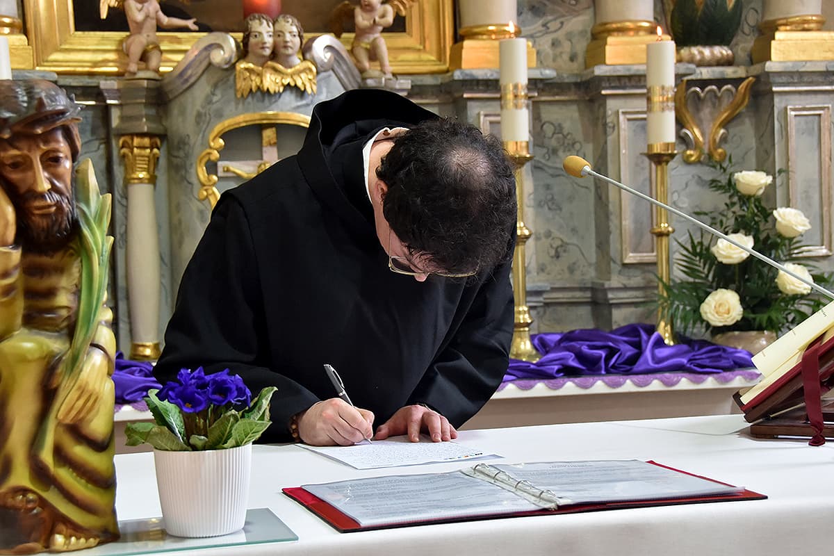 Das Bild zeigt Frater Philipp beim Unterschreiben der Professurkunde.