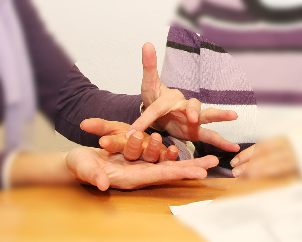 Mit den Händen werden Buchstaben in die Hand des anderen getippt