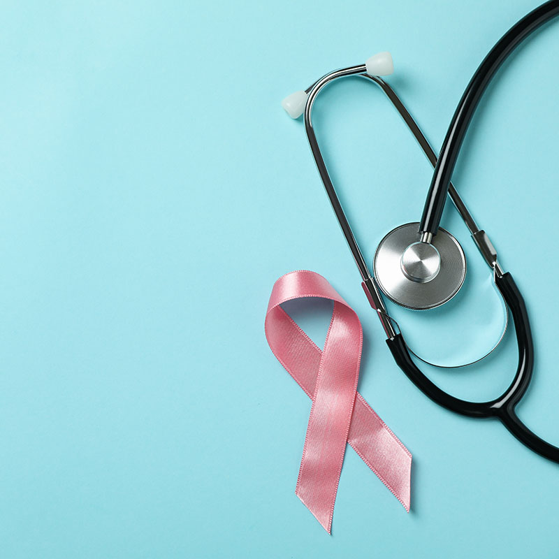 Pink awareness ribbon and stethoscope on blue background