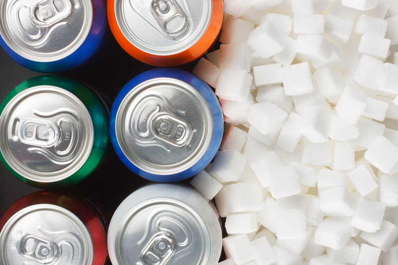 Sugar in carbonated drinks / airborne77 - stock.adobe.com Unhealthy food concept - sugar in carbonated drinks. Sugar cubes as background and canned drink