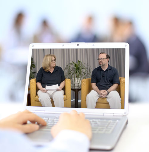 Das Bild zeigt einen Laptop auf dem ein Standbild einer Diskussionsrunde mit einer Frau und einem Mann angezeigt wird.