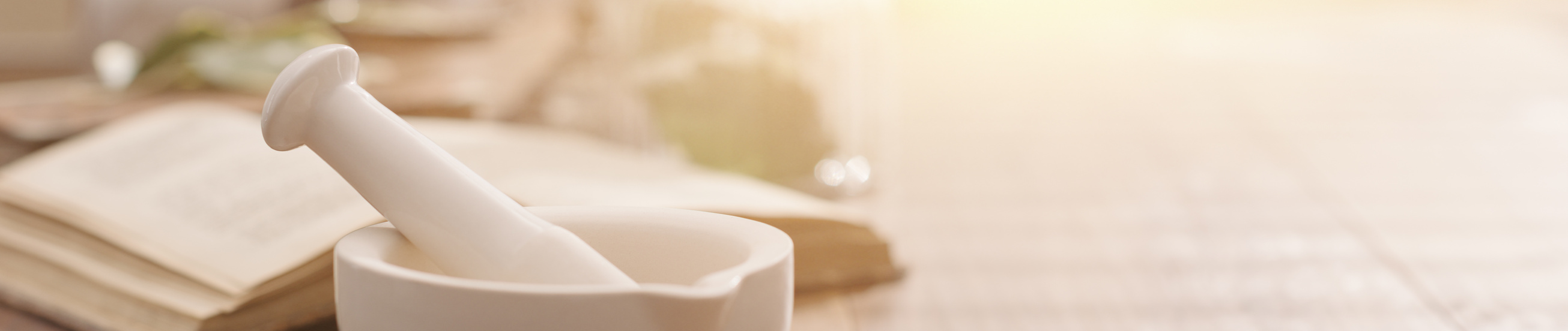 Mortar and pestle with pharmaceutical preparations's book and herbs on a wooden pharmacist table, traditional medicine and pharmacy concept