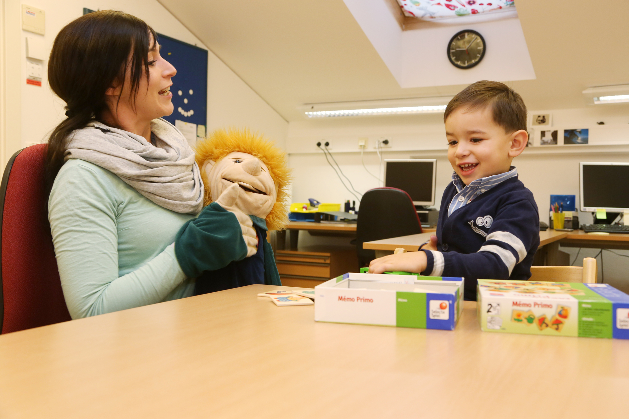 Eine Betreuerin mit einer Handpuppe spielt mit einem kleinen Jungen.