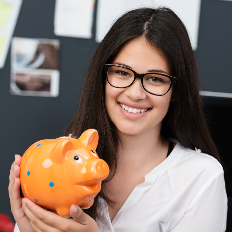lächelnde schülerin hält sparschwein in der hand