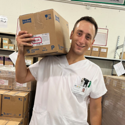 Ein Mitarbeiter trägt ein Paket ins Lager.