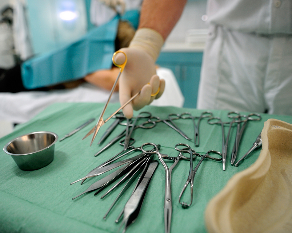 Zu sehen ist ein Arzt, der OP Besteck hält. 