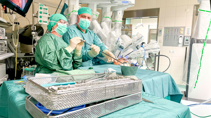 Arzt und sterile Pflegekraft mit Operationsroboter