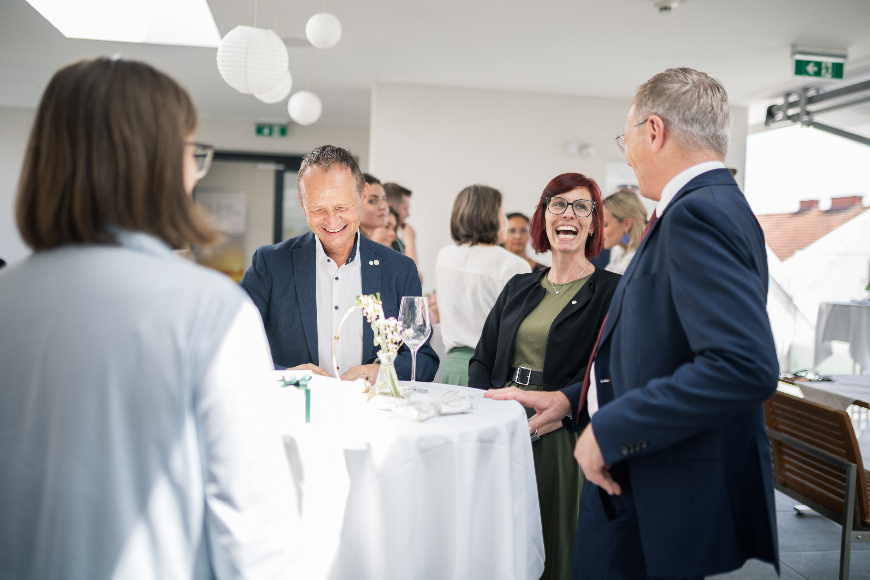 Der Landeshauptmann spricht an einem runden Stehtisch mit einem Mann und einer Frau.