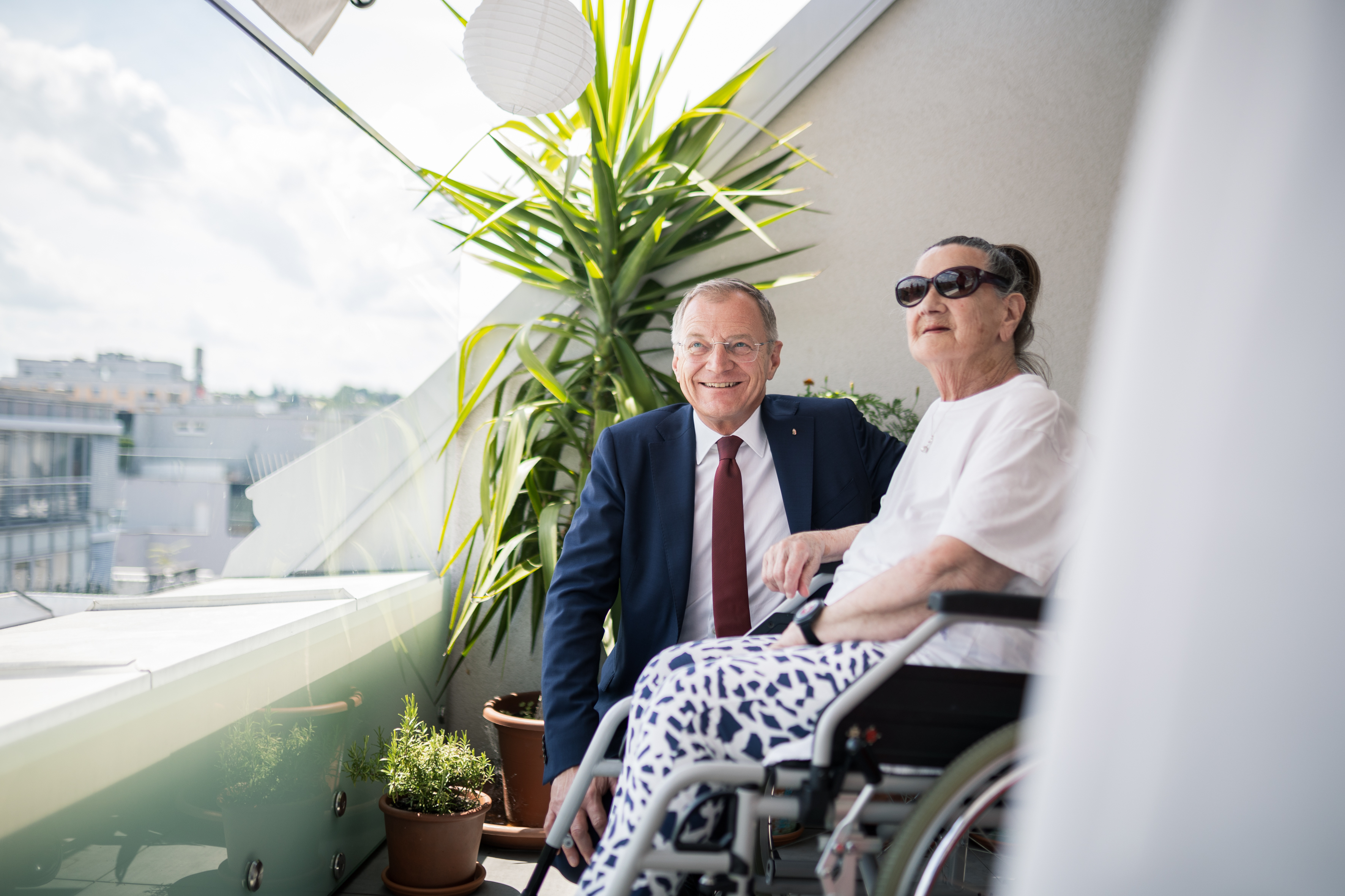 Das Bild zeigt Landeshauptmann Thomas Stelzer mit einer Bewohnerin im Rollstuhl.
